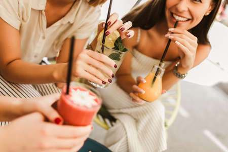 Beautiful girls drinking cocktail in cafe and having fun.