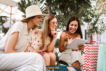 Happy young women using digital tablet in cafe outdoor