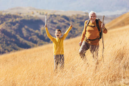 Senior man with grandson on country walk in autumn.の写真素材
