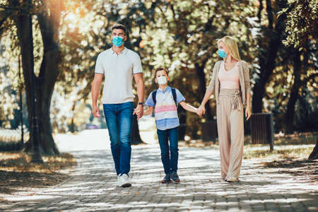 Mother,father and little son wearing face protective medical mask for protection from virus disease in park.の写真素材