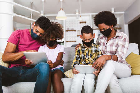 Family at home.African american family wearing protective masks using digital tablet at home.