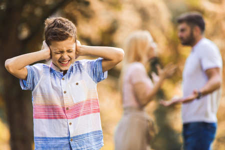 Sad, desperate little boy during parents quarrel. Clog the ears.