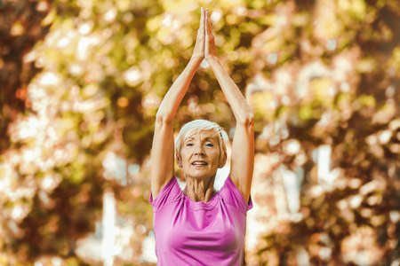 Senior woman doing yoga exercises at park.の写真素材