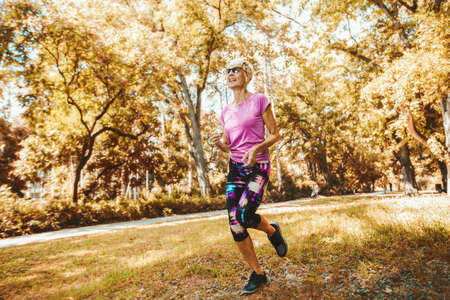 Elderly woman running with headphones in the park