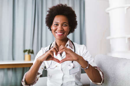 Portrait of happy black healthcare worker gesturing with hands looking at camera.の写真素材