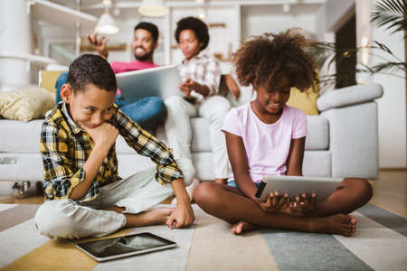 African american boy and girl lying on floor and using digital tablet. Family at home.の写真素材