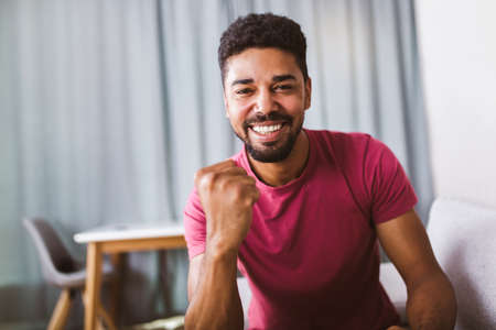 Portrait of smiling african american man, arm fists pumped celebrating success.の写真素材