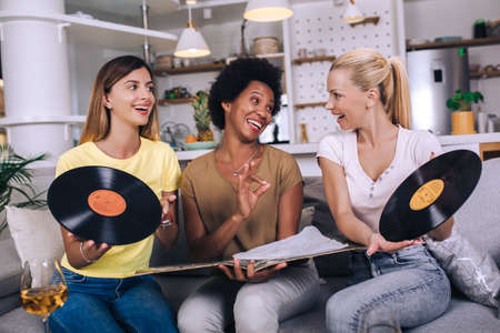 Happy young female friends at home listening vinyl at home. Choosing next record.の写真素材