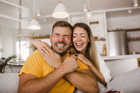 Happy man looking at a watch given by his girlfriend at homeの写真素材