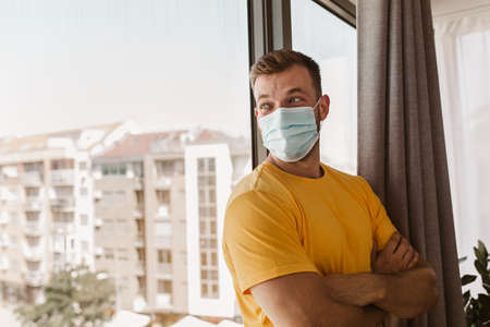 Coronavirus pandemic covid-19 and quarantine concept. Man in a medical mask near window