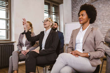 Female entrepreneur raising hand to answer the question during business presentation in the office.の写真素材