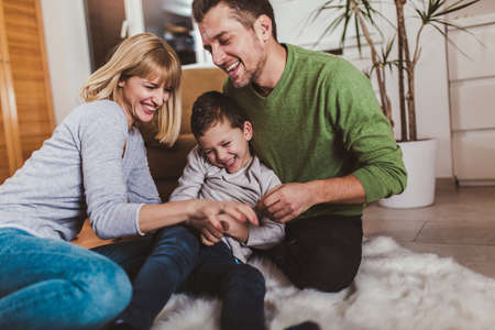 Family sitting on floor and playing together at home. Selective focus.の写真素材