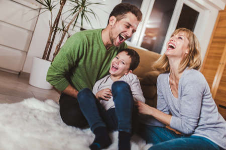 Family sitting on floor and playing together at home. Selective focus.の写真素材