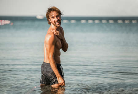 Handsome young man posing on the beach by the sea