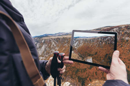 Man on a hiking photographs nature with a digital tabletの写真素材