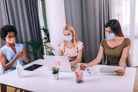 Female business colleagues with face masks working in the office
