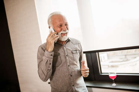 Smiling senior man on a phone call in living room