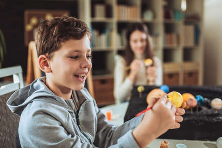 Happy school boy and girl  making a solar system for a school science project at home