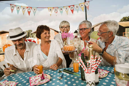 Senior people celebrating birthday in the cottage on the river having fun.の写真素材