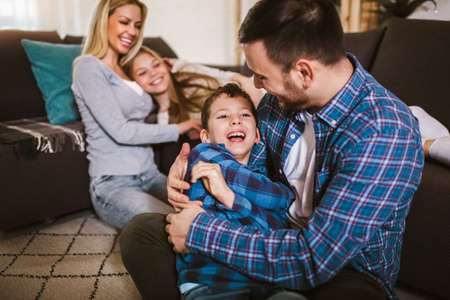 Happy family with kids playing at home. Family sitting on floor and playing together.の写真素材