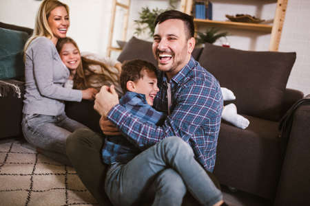 Happy family with kids playing at home. Family sitting on floor and playing together.の写真素材