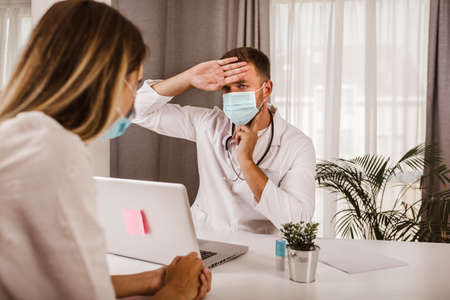 Doctor communicating with a patient while wearing protective face mask during medical appointment.の写真素材