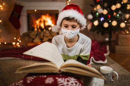 Boy meets Christmas in the covid-19 pandemic. Child in a protective medical mask. Quarantine isolation social distance. New year holidays.の写真素材
