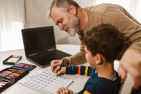 Child practicing writing at home with the help of his father