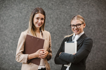 Portrait of two successful businesswomen holding digital tablet and clipboardの写真素材
