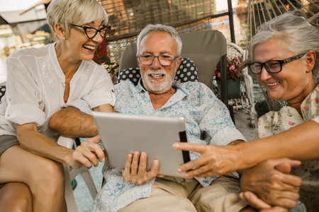 Group of senior friends with eyeglasses using digital tablet, having fun.の写真素材