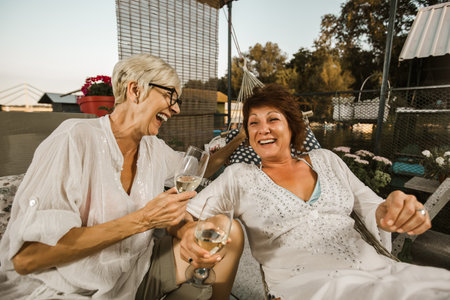 Senior female friends enjoying a day in the cottage near the river, having fun.の写真素材