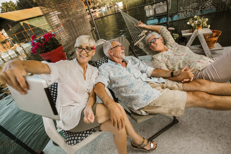 Group of senior friends with eyeglasses using digital tablet, having fun.