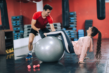 Fitness instructor with girl on training in fitness centerの写真素材