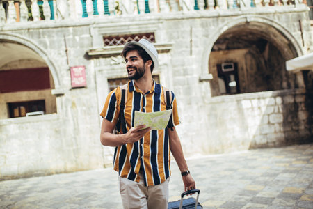 Happy tourist with backpack is making travel across city uses a map for orientation.の写真素材