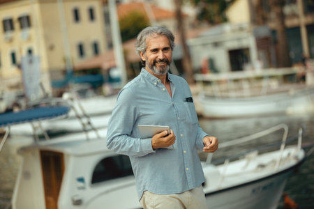 Portrait of retirement handsome senior man holding tablet computer on seafrontの写真素材