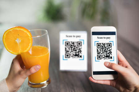 Women's hands are using the phone to scan the qr code to pay juice. Scan to get discounts or pay for juice. The concept of using a phone to transfer money or paying money online without cash.の写真素材