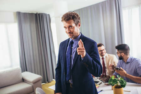 Leader ceo or professional business coach looking at camera posing in office with diverse happy team at background.の写真素材
