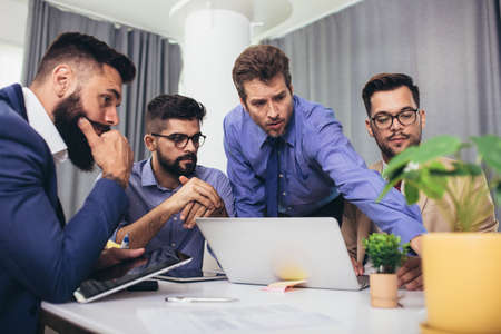Colleagues at meeting in boardroom, sitting at table together, sharing ideas, discussing project strategy.の写真素材