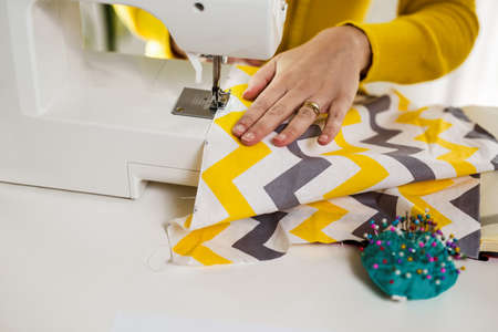 Woman seamstress work on the sewing-machine, close up.