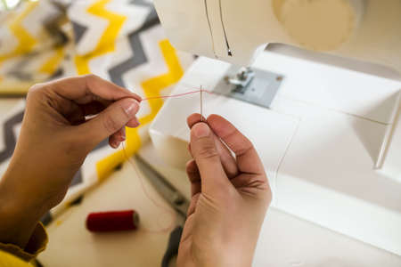 Woman sewing on a sewing machine at her home, close up.の写真素材