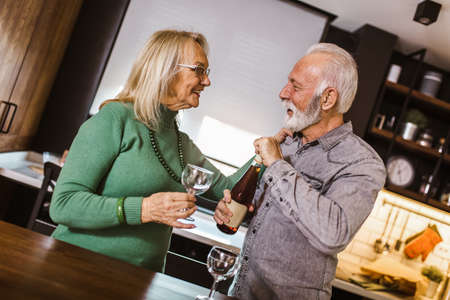 Senior couple choosing wine in the kitchen.