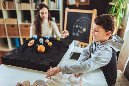 Happy school boy and girl  making a solar system for a school science project at home