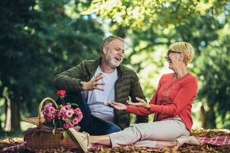 Happy senior couple having a picnic in parkの写真素材