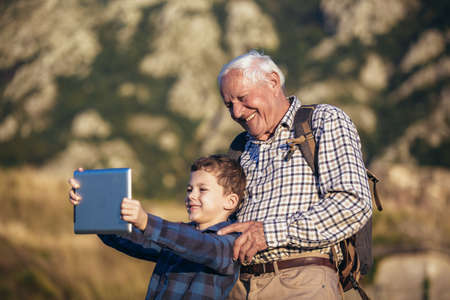 Grandfather and grandson hiking, using digital tablet.の写真素材