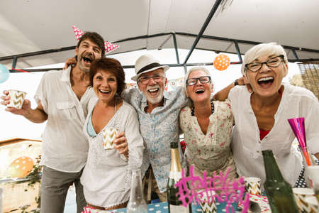 Senior people celebrating birthday in the cottage on the river having fun.の写真素材