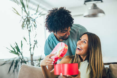 Man giving a surprise gift to woman at homeの写真素材