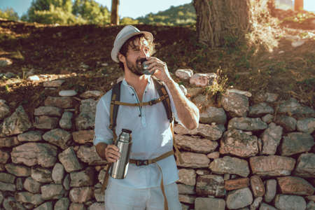 Traveling man with with backpack resting drink coffee.