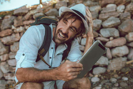 Traveling man with with backpack resting using digital tablet.の写真素材
