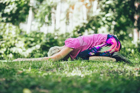 Happy mature woman practicing yoga in park. Active lifestyleの写真素材