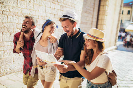 Group of tourists searching for places on their map outdoors.の写真素材